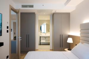 a bedroom with a white bed and a bathroom at RMH Modena Raffaello in Modena