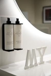 two bottles ofodorizers sitting on a table next to a lamp at RMH Modena Raffaello in Modena
