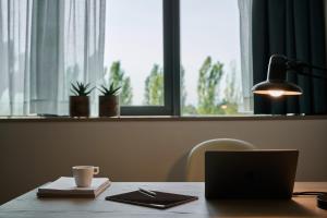 a desk with a laptop computer and a lamp at RMH Modena Raffaello in Modena