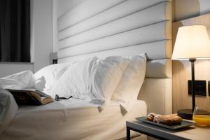 a bed with white sheets and a table with a lamp at RMH Modena Raffaello in Modena