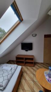 Cette chambre comprend un lit, une télévision et une table. dans l'établissement Zajazd Stradomia, à Stradomia Wierzchnia