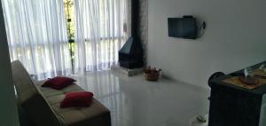 uma sala de estar com um sofá e uma televisão em Casa de Campo em Lumiar com corrego ,lareira e churrasqueira em Lumiar