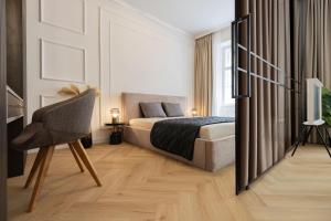 a bedroom with a bed and a chair and a television at GENeve - old town apartment Bratislava in Bratislava