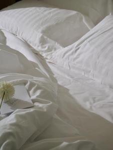 a white bed with a book and a flower on it at RMH Modena Raffaello in Modena