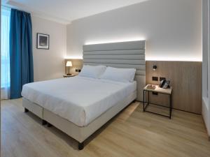 a bedroom with a large white bed and two tables at RMH Modena Raffaello in Modena