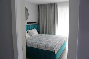 - une chambre avec un lit doté d'une couverture bleue et d'une fenêtre dans l'établissement Blue Apartment Mamaia Nord, à Mamaia