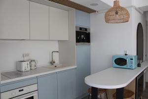 une cuisine avec des placards blancs et un four micro-ondes bleu sur un comptoir dans l'établissement Blue Apartment Mamaia Nord, à Mamaia