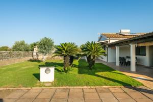 a yard with palm trees and a house at Casa Silvia in Calasetta