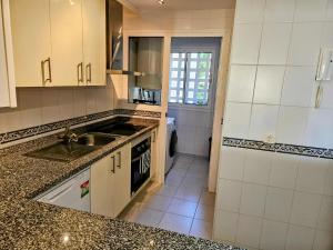 een keuken met een wastafel en een fornuis top oven bij Ground floor 2 bed apartment with 5 pools and large terrace in Manilva