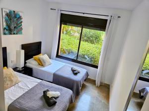 twee bedden in een kamer met een groot raam bij Ground floor 2 bed apartment with 5 pools and large terrace in Manilva