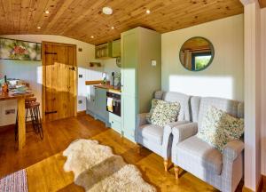 a living room with a couch and a kitchen at Abberley Shepherds Hut - Ockeridge Rural Retreats in Wichenford