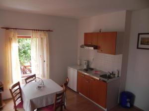 a kitchen with a table and a small kitchen with a window at Apartments Riva in Pag