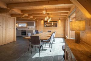 a dining room with a wooden table and chairs at Beau chalet GUSTAVE 4 chambres 50m piste Huez Express in LʼHuez