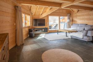 a living room with a couch and a tv at Beau chalet GUSTAVE 4 chambres 50m piste Huez Express in LʼHuez