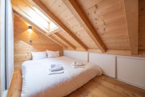 a bed in a room with a wooden ceiling at Beau chalet GUSTAVE 4 chambres 50m piste Huez Express in LʼHuez
