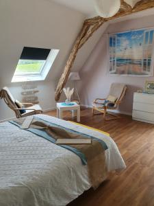 ein Schlafzimmer mit einem Bett und Stühlen im Dachgeschoss in der Unterkunft Au fil des saisons in Grézillé