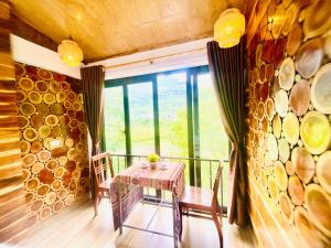 a table and chairs in a room with a stone wall at Homestay Quân Hằng in Mai Châu