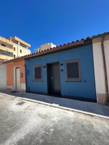 un edificio blu con una porta in un parcheggio di 2 Room Suite Monte Nero- Best price vs quality-Fully equipped & renovated- City Centre a Olbia