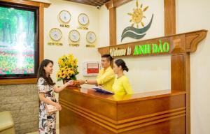 Un uomo e due donne in piedi davanti a un registratore di cassa. di Anh Đào Hotel & Apartment a Da Nang