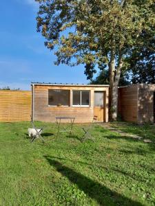 une maison avec deux chaises et une table dans une cour dans l'établissement Gîte L'ÉRABLE, à Chamant