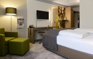 a hotel room with a bed and a desk and a chair at ACHAT Hotel Regensburg im Park in Regensburg