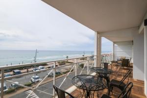 d'un balcon avec des tables et des chaises et une vue sur l'océan. dans l'établissement Appartement - vue exceptionnelle, à Lacanau-Océan