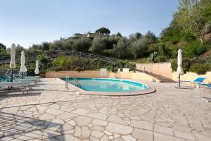 una piscina con sillas y sombrillas en un patio en gli ulivi di montalbano 1, en La Spezia