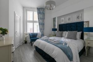 Kent的住宿－Luxury 1BR Broadstairs: 2 mins walk to the beach，一间卧室配有一张大床和蓝色床头板