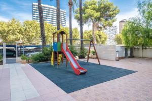 a playground with a slide in a park with palm trees at Torre Yago Apartment 15-2 Levante Beach in Benidorm