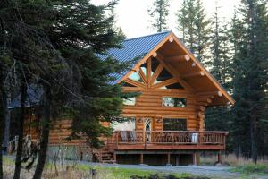 uma cabana de madeira com um deque na floresta em Anchor Point Captain Cook Lodge em Anchor Point