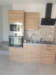 a kitchen with wooden cabinets and a microwave and a sink at spacieux T2 confortable in Saint-Vallier