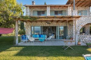 Casa de piedra con patio con sillas azules en Villa Leon, en Chalkida