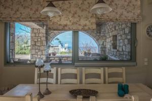 a dining room with a table and two windows at Villa Leon in Chalkida
