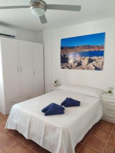 Un dormitorio blanco con una cama con almohadas azules. en Apartamento El Flamenco Azul Cabo de Gata, en Almería