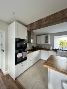 a kitchen with white cabinets and a wooden table at The Carthouse (Luxury 2 bed with private hot tub) in Newburgh