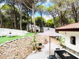 une terrasse avec un parasol et un mur en pierre dans l'établissement Luxury private Villa 25m Pool, Gym, 200m to Beach, à Cañet de Mar