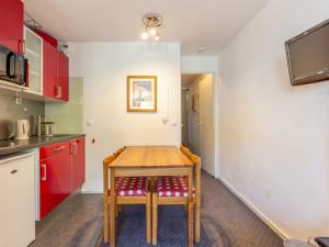 eine Küche mit einem Holztisch und roten Schränken in der Unterkunft Studio chaleureux à Val-d'Isère avec WIFI, animaux acceptés - FR-1-694-52 in Val dʼIsère
