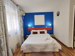 Dormitorio azul con cama blanca y pared azul en Pensiunea & SPA Boema Ploiesti, en Ploieşti