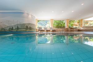 una piscina cubierta con suelo de baldosa azul y ventanas en Sonnleiten Sterngucker 7, en Collepietra