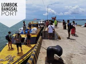 a group of people standing on a dock next to a boat at Gili Ferries Manta Express in Padangbai