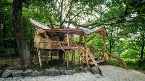 una casa en el árbol con un parque de madera en el bosque en Farkaskútvölgy en Felsőtold