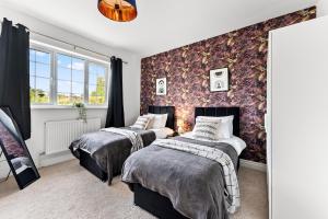 a bedroom with two beds and a wall with floral wallpaper at Stunning 4 Bed House - Sleeps 12 in Cheltenham