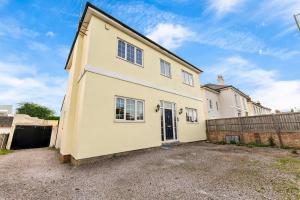 a large yellow house with a fence in front of it at Beautiful 4 Bed House - Sleeps 12 in Cheltenham