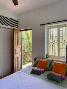 una camera da letto con un letto con cuscini arancioni e una finestra di Kiki Peaceful Studios Mandrem a Mandrem