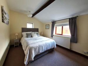 - une chambre avec un grand lit et une fenêtre dans l'établissement The Barn at Whitehouse Farm nr Salisbury & New Forest, à East Grimstead