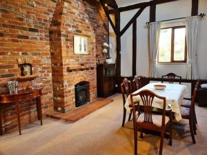a dining room with a table and a brick fireplace at The Barn at Whitehouse Farm nr Salisbury & New Forest in East Grimstead