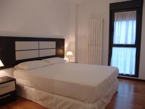 a bedroom with a large white bed and two windows at Apartamento Golf Rioja Alta in Cirueña