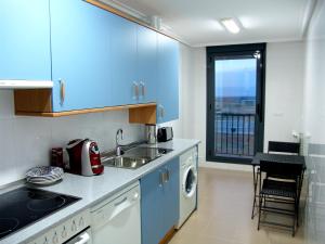 cocina con armarios azules, fregadero y ventana en Apartamento Golf Rioja Alta, en Cirueña