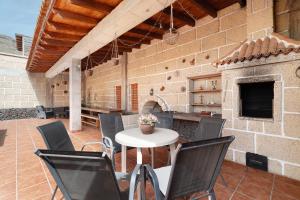 patio ze stołem, krzesłami i kominkiem w obiekcie Bonita Casa Arianny con Piscina w Aronie