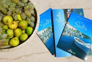 two books sitting next to a bowl of fruit at Small stone house in a quiet place island Solta in Stomorska